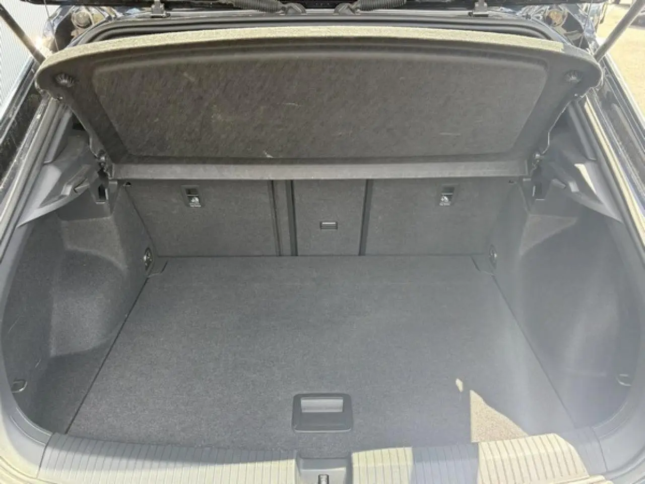 Coffre ouvert vu de l'arrière d'un Volkswagen T-Roc noir intense, montrant un espace de chargement vide et propre.