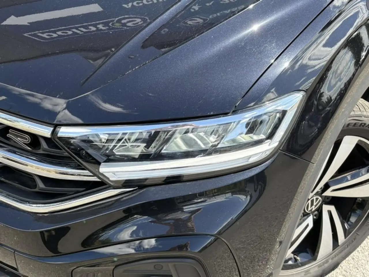 Gros plan sur l'avant droit noir intense du Volkswagen T-Roc 2025 R-Line, mettant en valeur le phare LED et la jante Nevada 18 pouces.