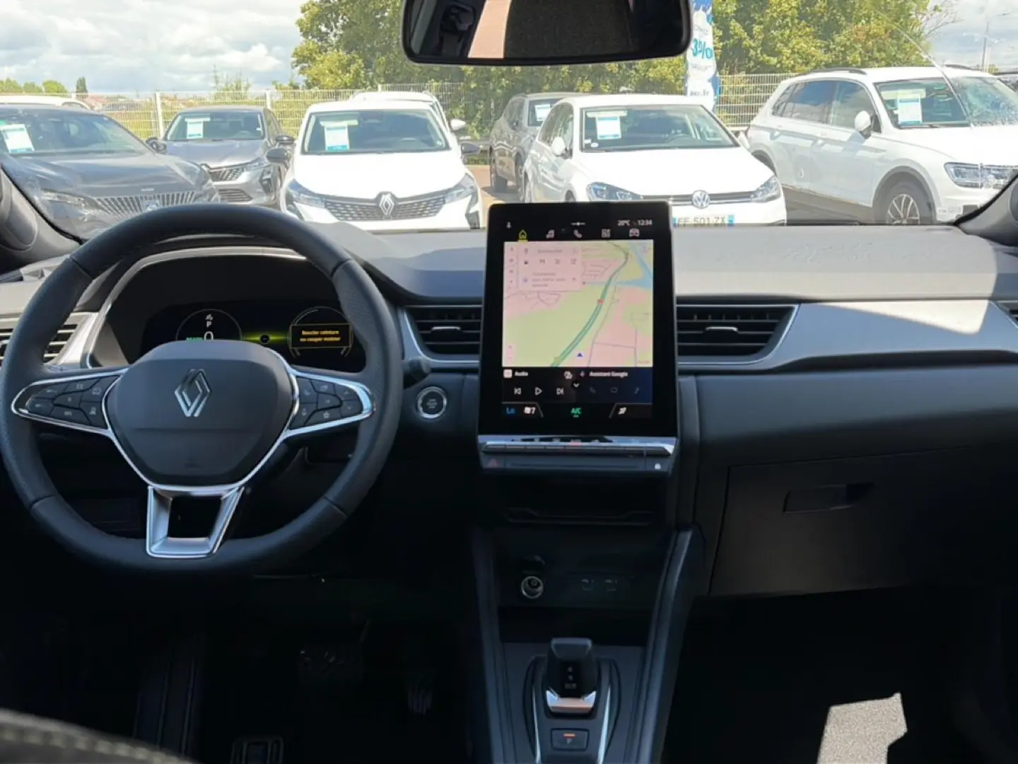 Vue intérieure avant du Renault Captur 2026, tableau de bord noir avec grand écran tactile central affichant une carte GPS.