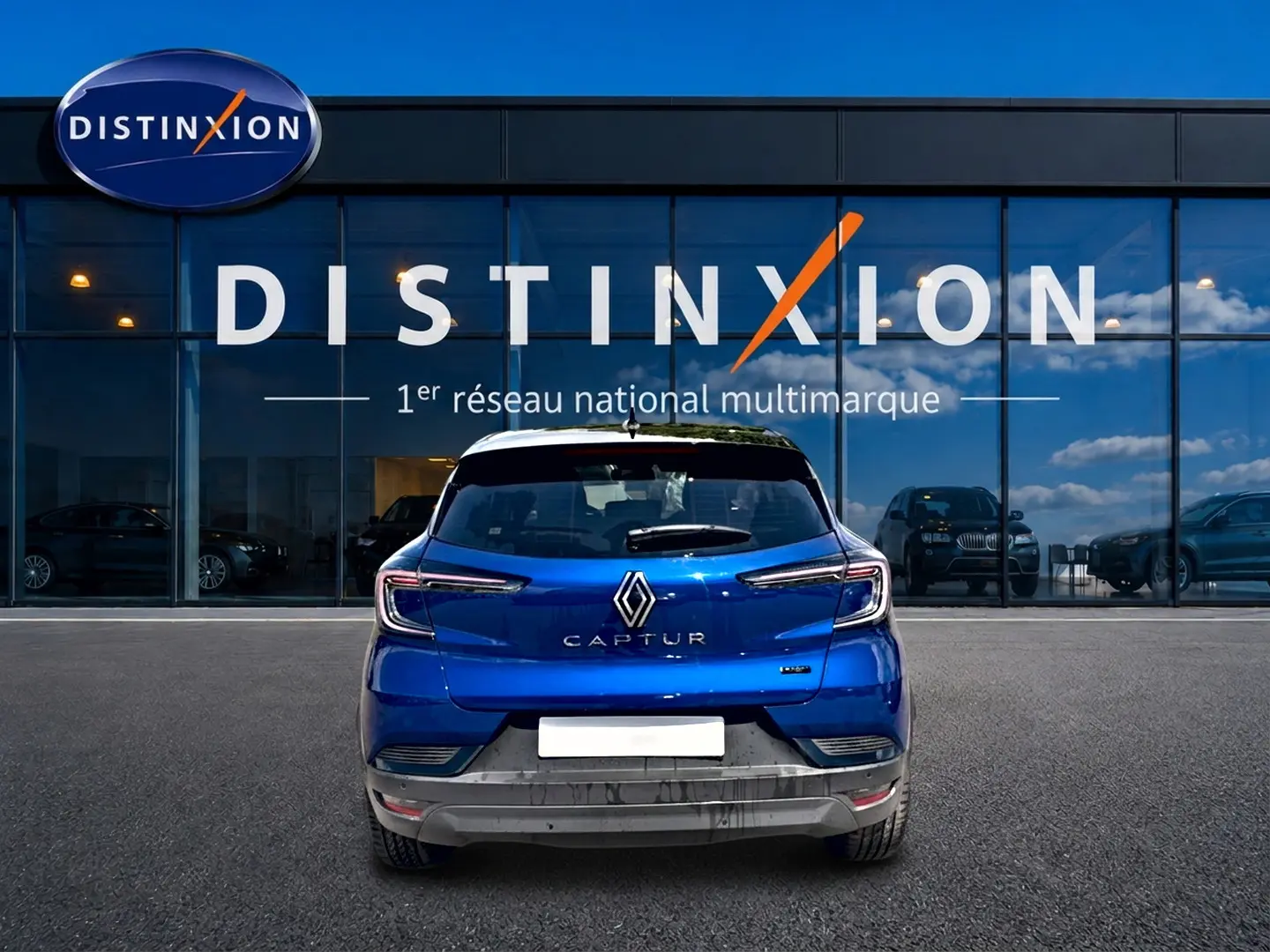 Vue arrière d'un Renault Captur bleu iron avec toit noir, garé devant une vitrine Distinxion.