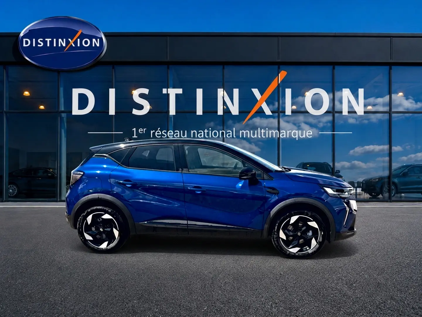 Renault Captur 2026 bleu iron toit noir, vue de profil côté gauche devant vitrine Distinxion.