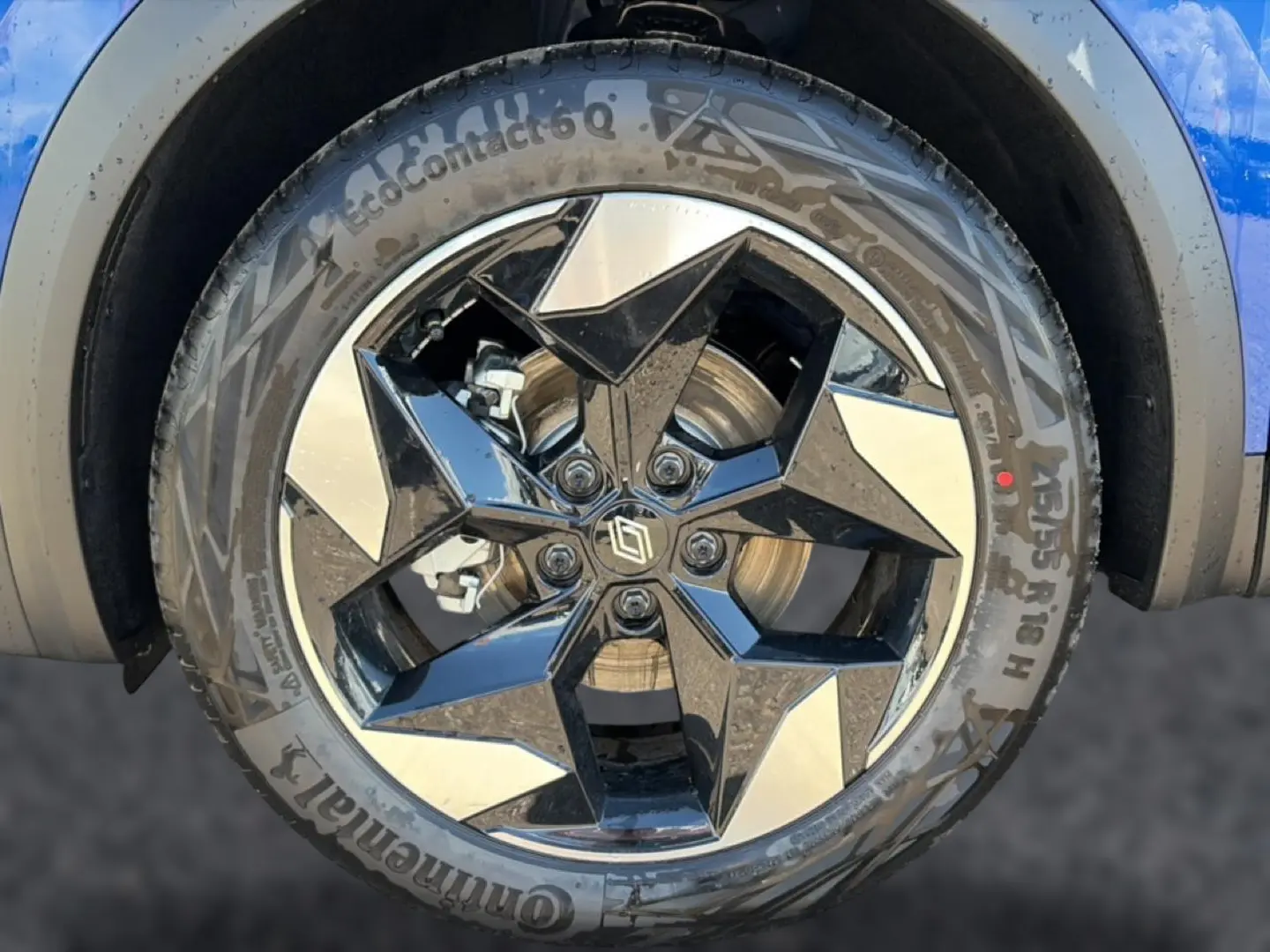 Gros plan sur la jante alu noire et argentée du côté avant droit du Renault Captur bleu iron avec toit noir.