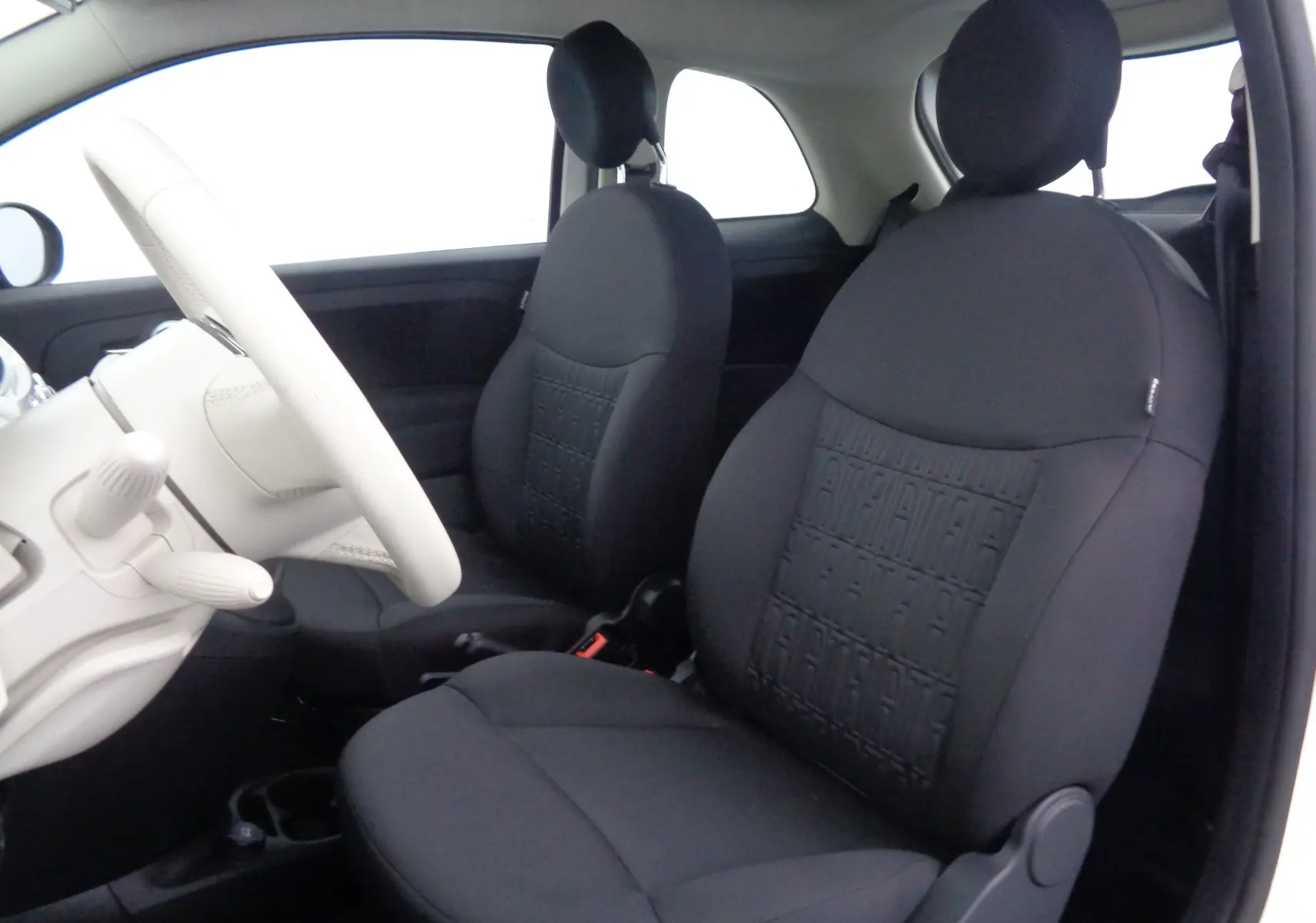 Intérieur de la FIAT 500 2023, vue côté conducteur, sièges noirs avec motifs et volant blanc Gelato.