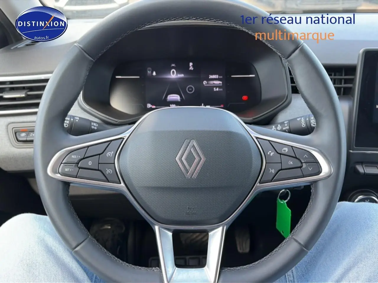 Vue intérieure centrée sur le volant multifonction gris et l'écran numérique du tableau de bord d'une Renault Clio V.