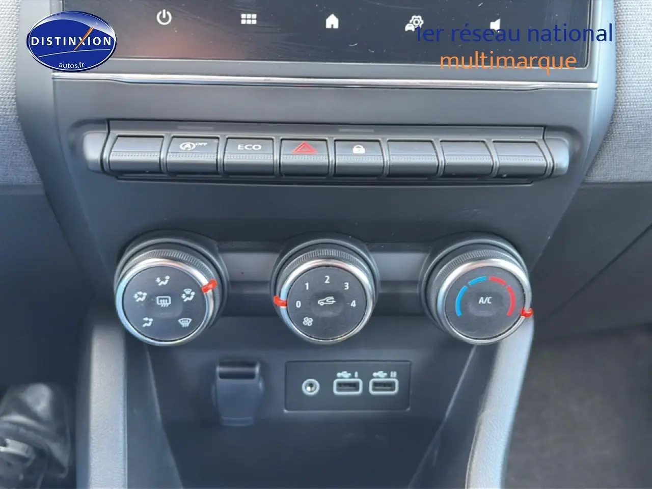 Vue rapprochée de la console centrale de la Renault Clio V 2025 gris métal, avec commandes climatisation et ports USB visibles.