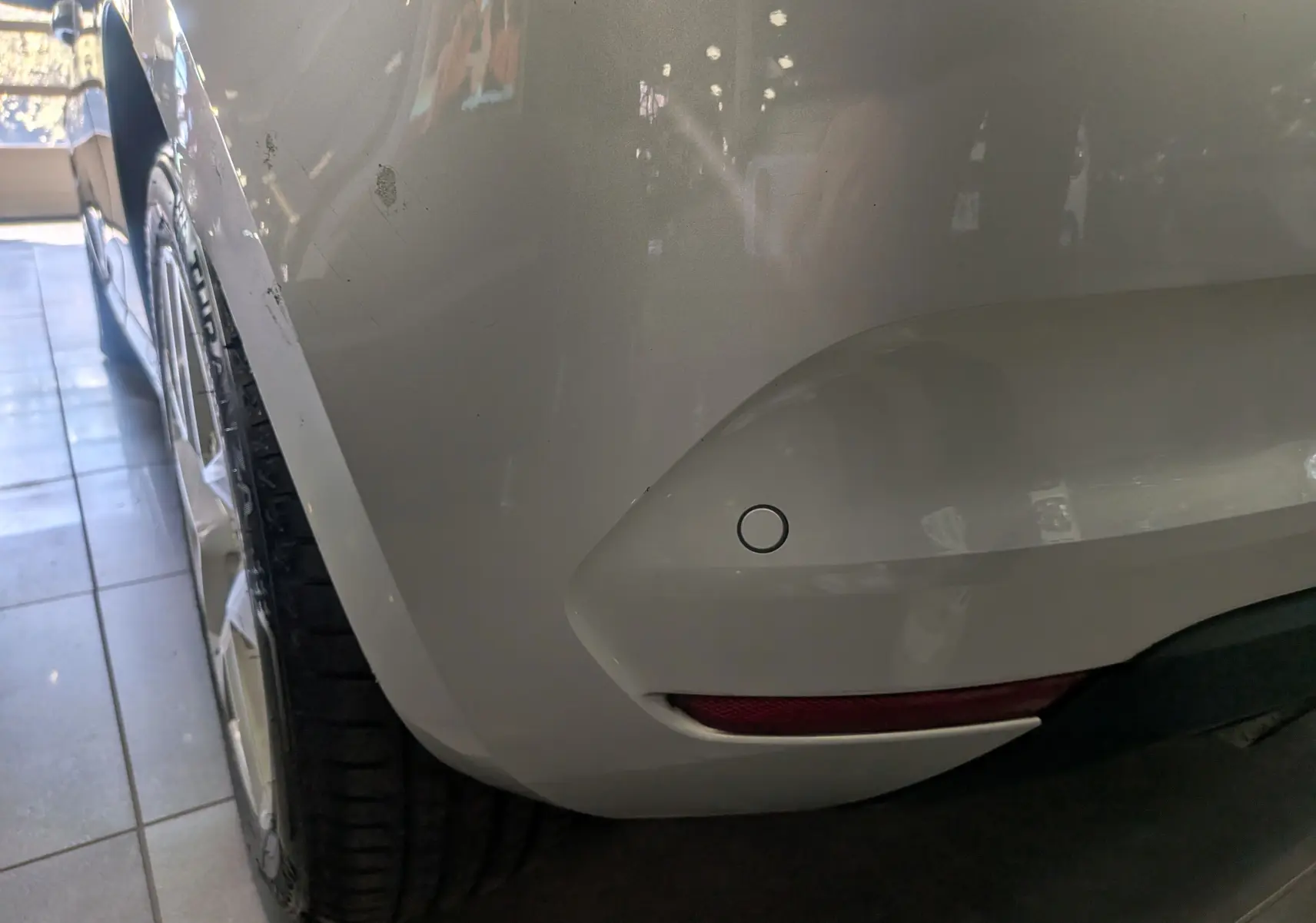 Gros plan sur l'angle arrière droit gris platine d'une Renault Clio V 2021, avec capteur de stationnement visible.