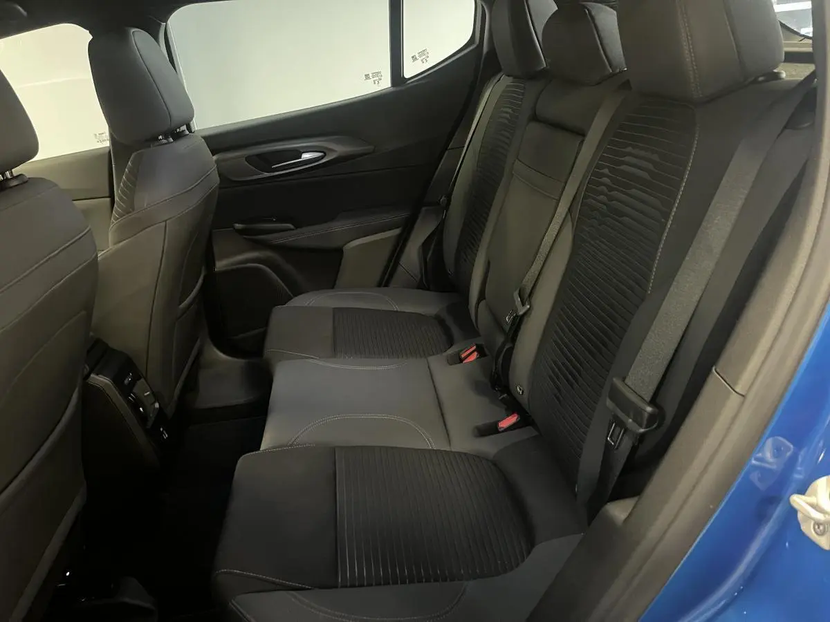 Vue intérieure côté droit sur la banquette arrière noire de l'Alfa Romeo Tonale bleu 2024 avec ceinture de sécurité.