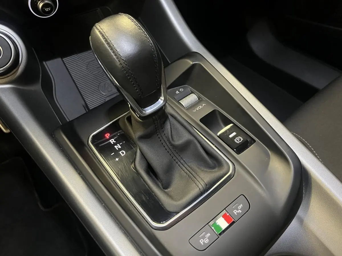 Gros plan sur la console centrale de l'Alfa Romeo Tonale 2024, levier de vitesse cuir noir et commandes de stationnement.
