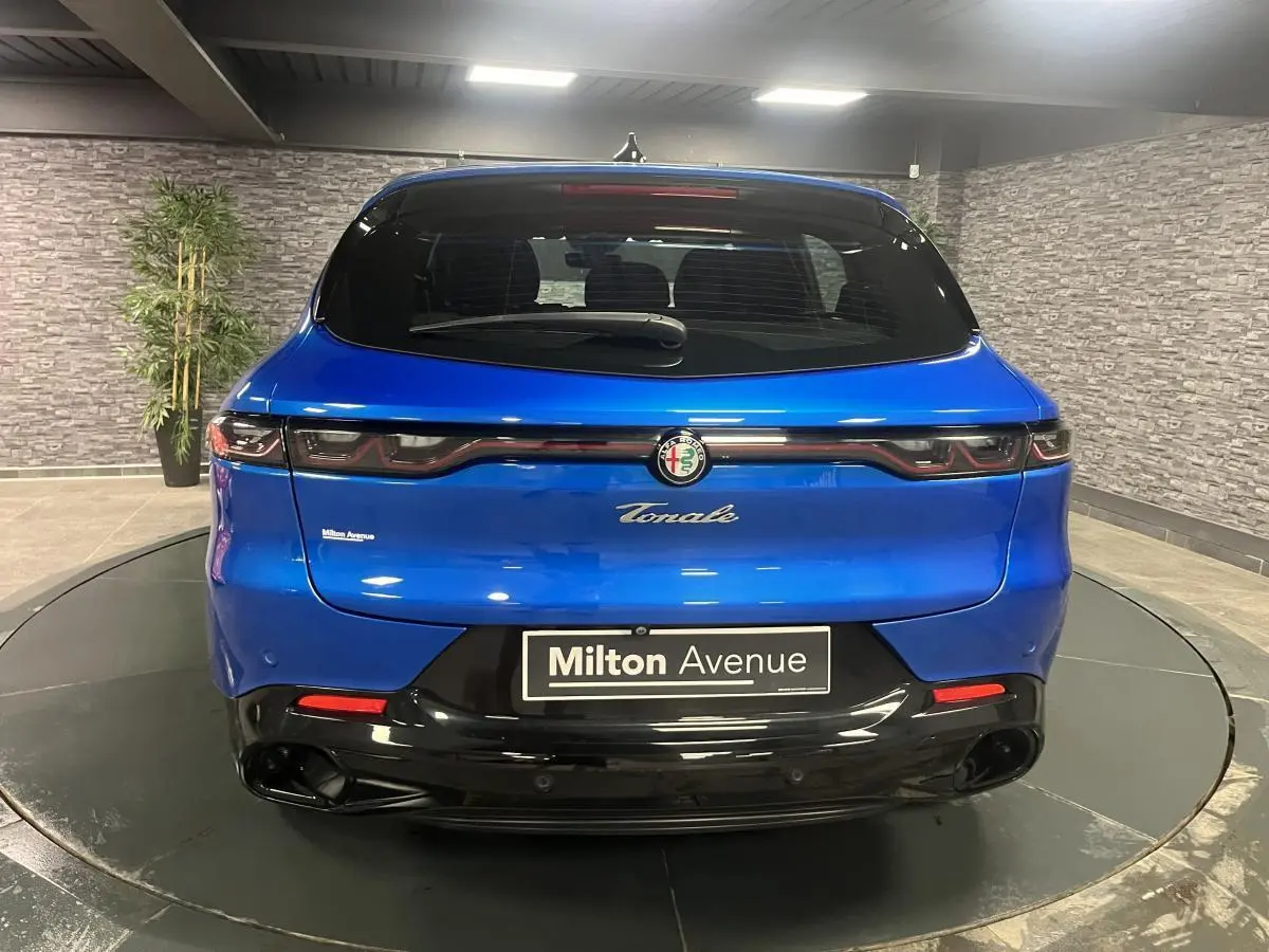 Vue arrière d'une Alfa Romeo Tonale bleu métallisé 2024 avec feux arrière LED et logo central sur fond noir brillant.