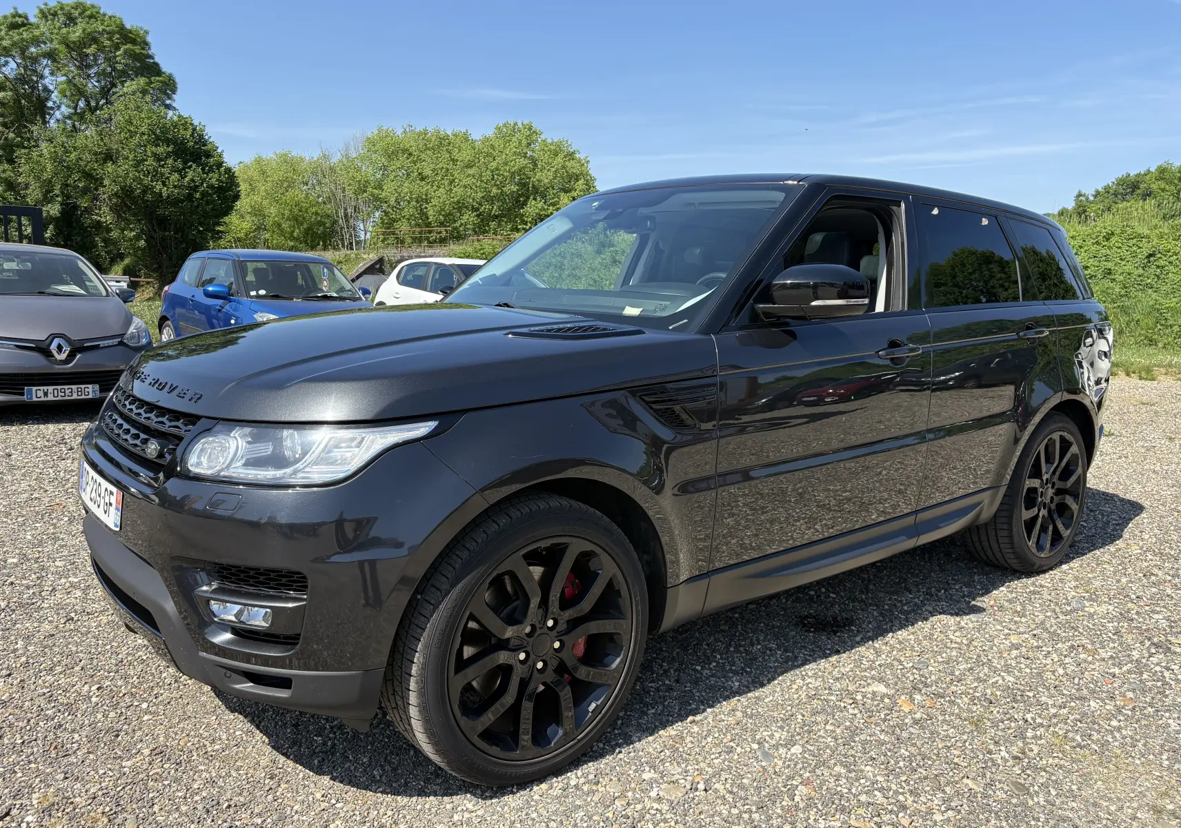 Vue 3/4 avant droite d'un Range Rover Sport Mark III gris foncé avec jantes noires et étriers rouges, stationné en extérieur.