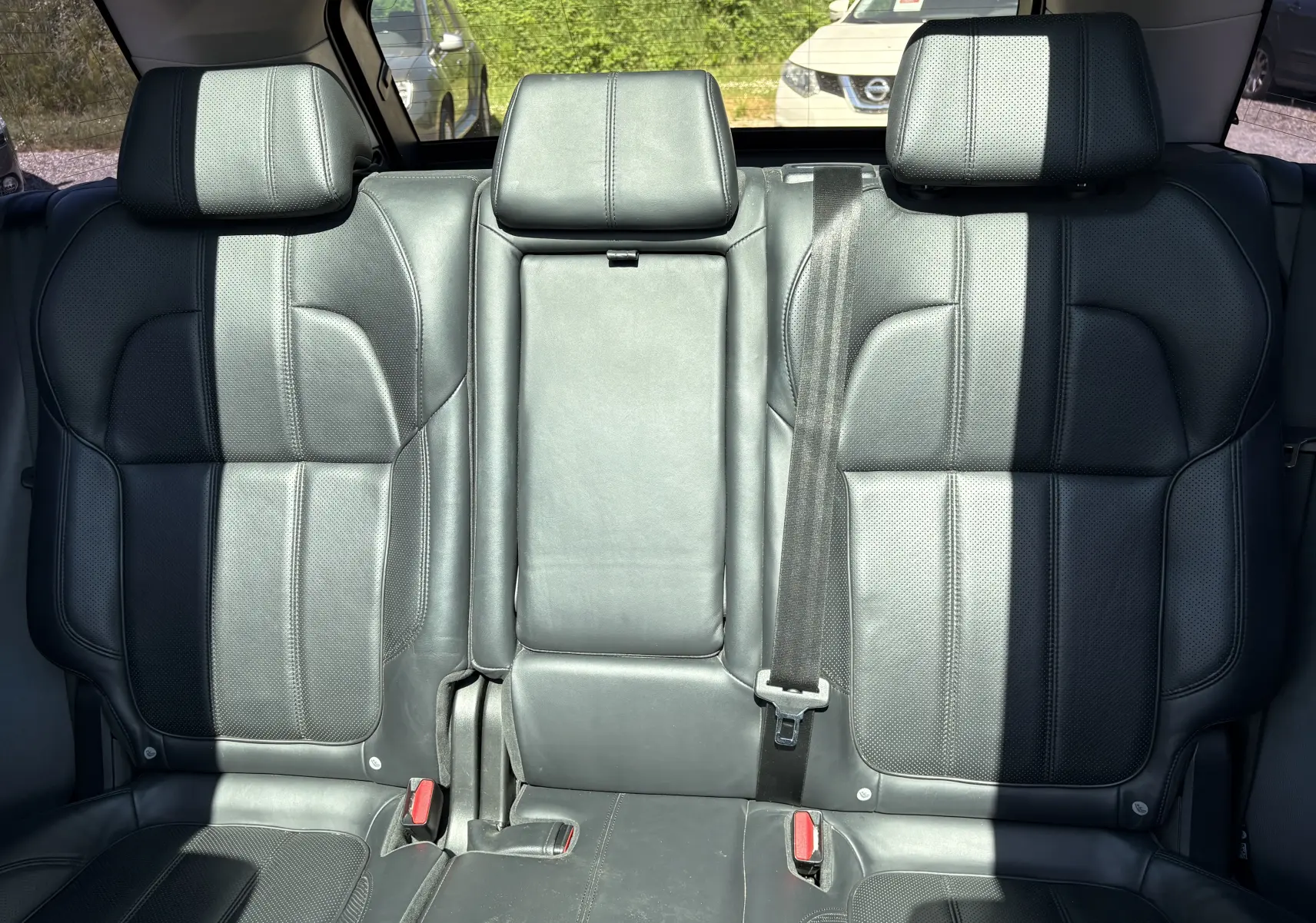 Vue intérieure montrant les sièges arrière en cuir noir du Range Rover Sport Mark III, avec appuie-têtes et ceinture de sécurité visible.