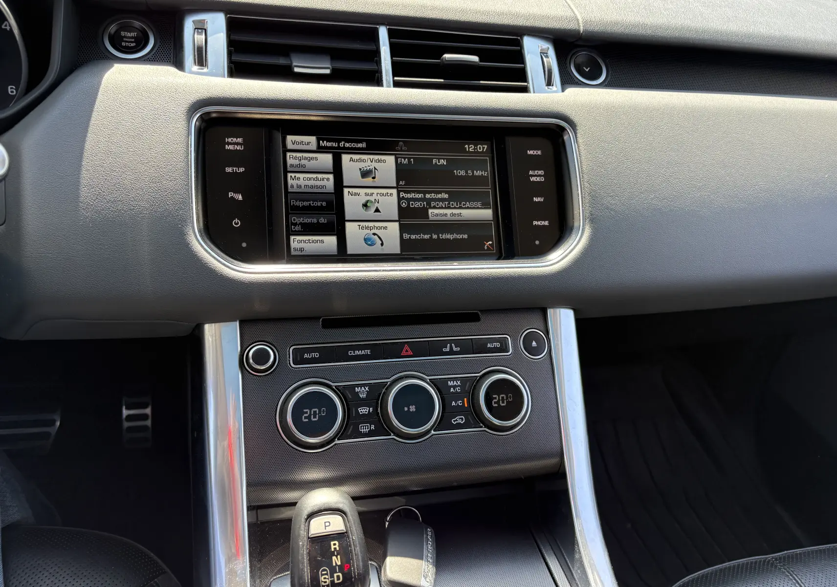 Vue rapprochée de la console centrale intérieure du Range Rover Sport 2015, avec écran tactile et commandes climatisation.