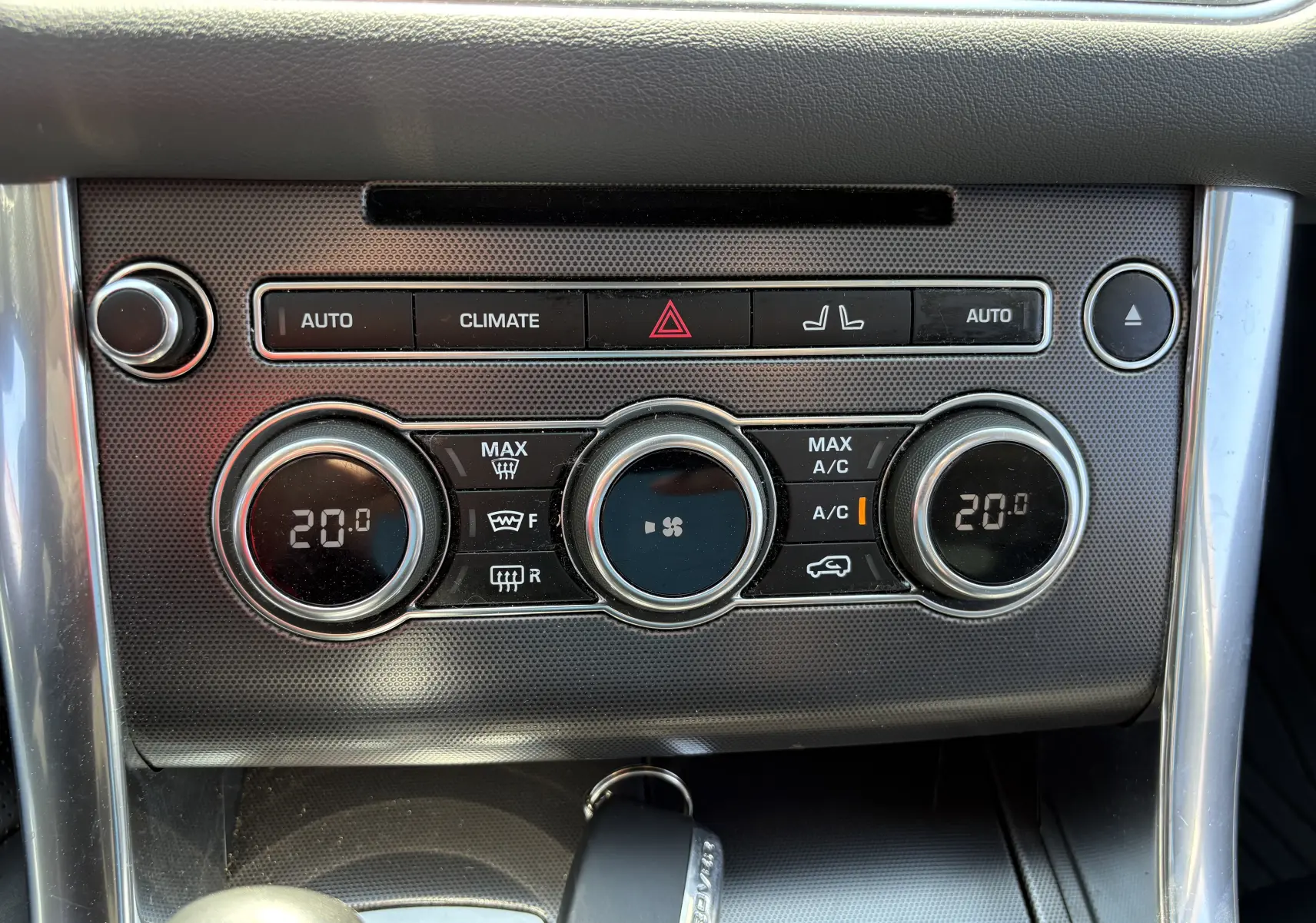 Détail du tableau de bord du Range Rover Sport 2015 montrant les commandes de climatisation à affichage digital à 20°C.