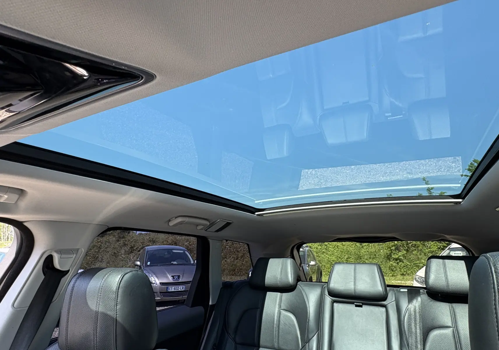 Intérieur du Range Rover Sport 2015 vu côté arrière, montrant le toit panoramique et les sièges en cuir noirs.