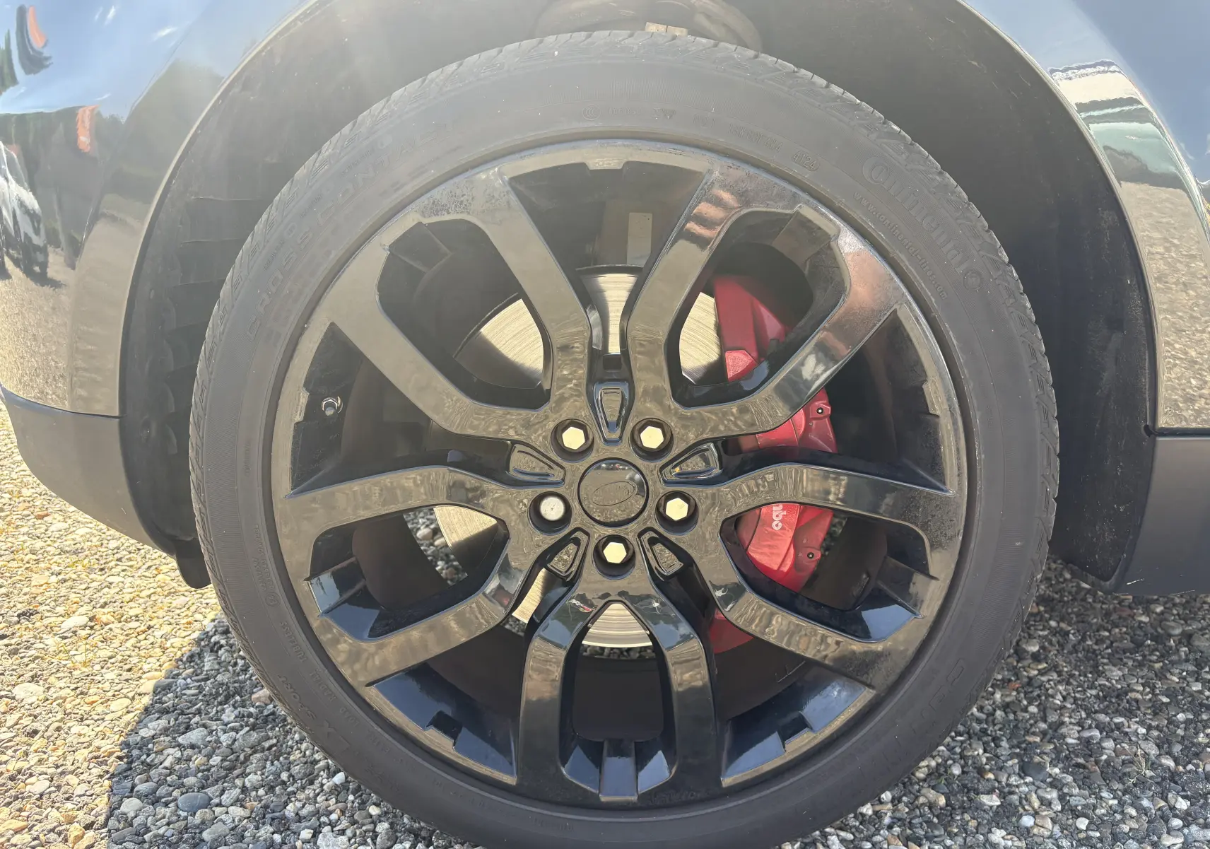 Gros plan sur la roue avant droite noire brillante d’un Range Rover Sport 2015 avec étrier de frein rouge Brembo.