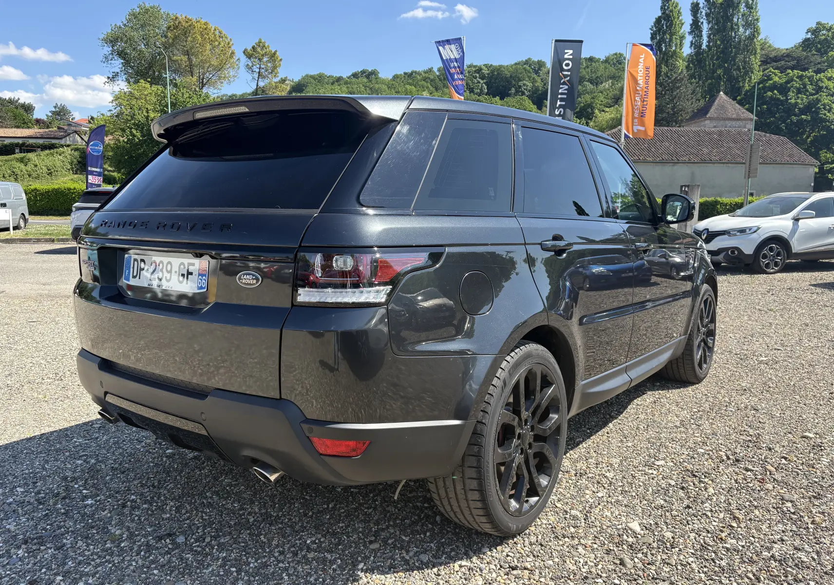 Vue 3/4 arrière droite d'un Range Rover Sport 2015 gris foncé avec jantes noires et vitres teintées.