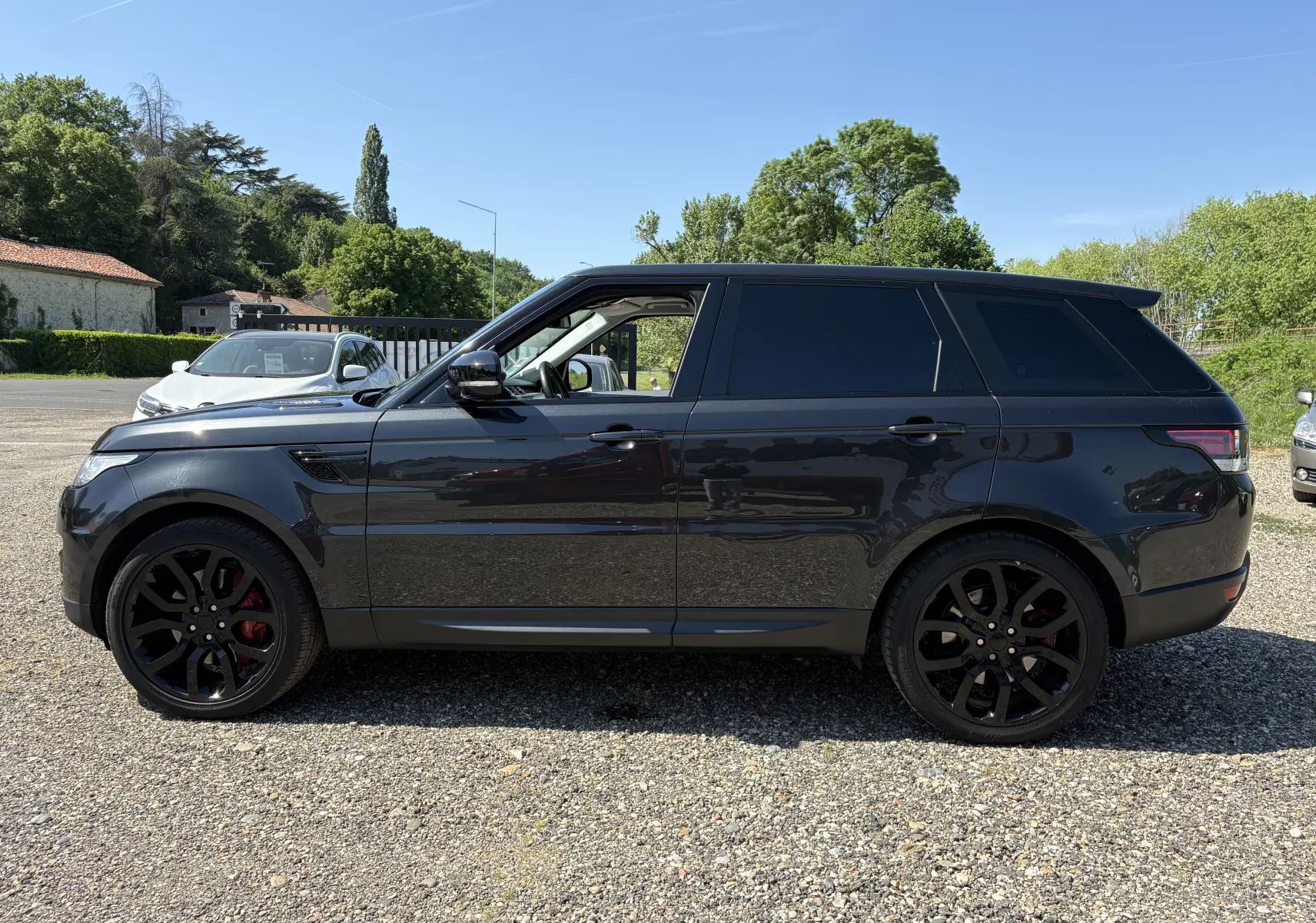 Range Rover Sport 2015 noir en vue de profil côté gauche, avec jantes noires et étriers de frein rouges visibles.