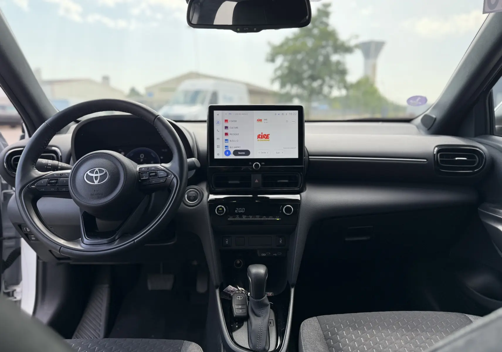 Vue intérieure avant de la Toyota Yaris Cross 130 CH Design 2024 avec écran tactile central et volant multifonction noir.