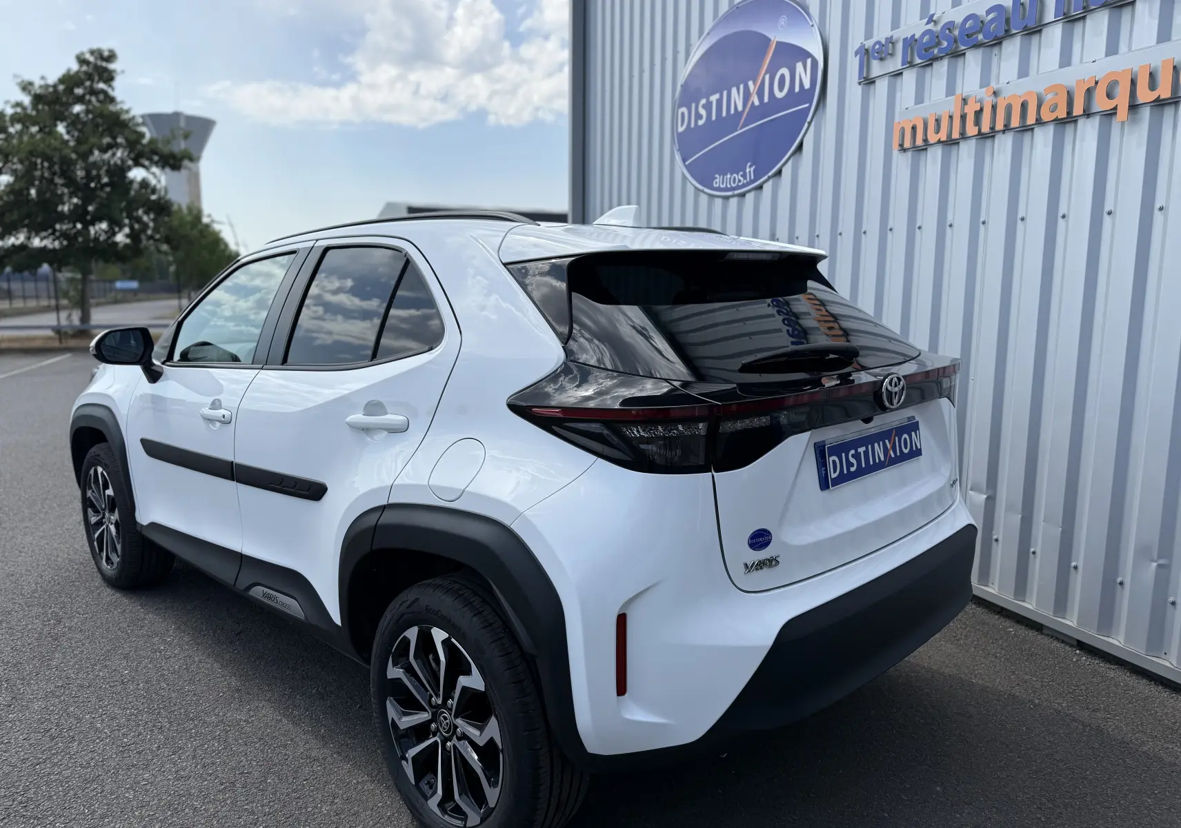 Vue 3/4 arrière droite d'une Toyota Yaris Cross 130 CH Design blanche avec toit noir et jantes bi-ton.