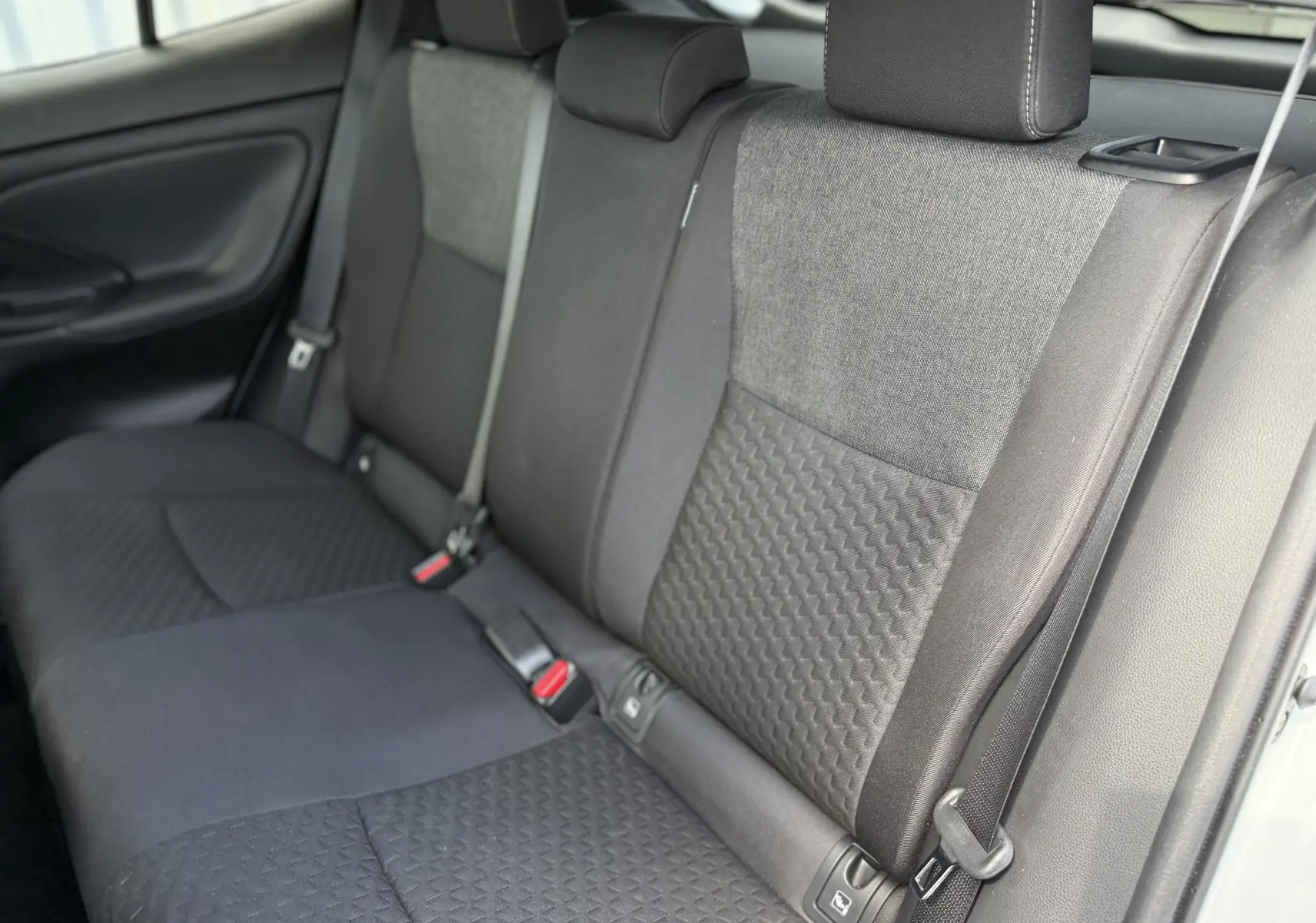 Vue intérieure du siège arrière droit en tissu gris et noir du Toyota Yaris Cross 130 CH Design 2024 hybride essence.