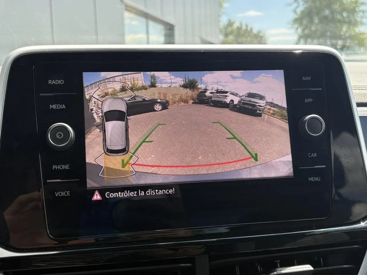 Écran tactile intérieur montrant la caméra de recul du Volkswagen T-Roc gris pyrite avec lignes de guidage vertes et rouges.