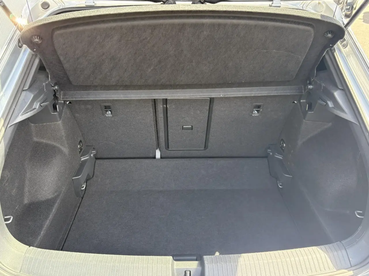 Coffre ouvert vu de l'arrière d'un Volkswagen T-Roc gris Pyrite, montrant un espace de rangement propre et spacieux.