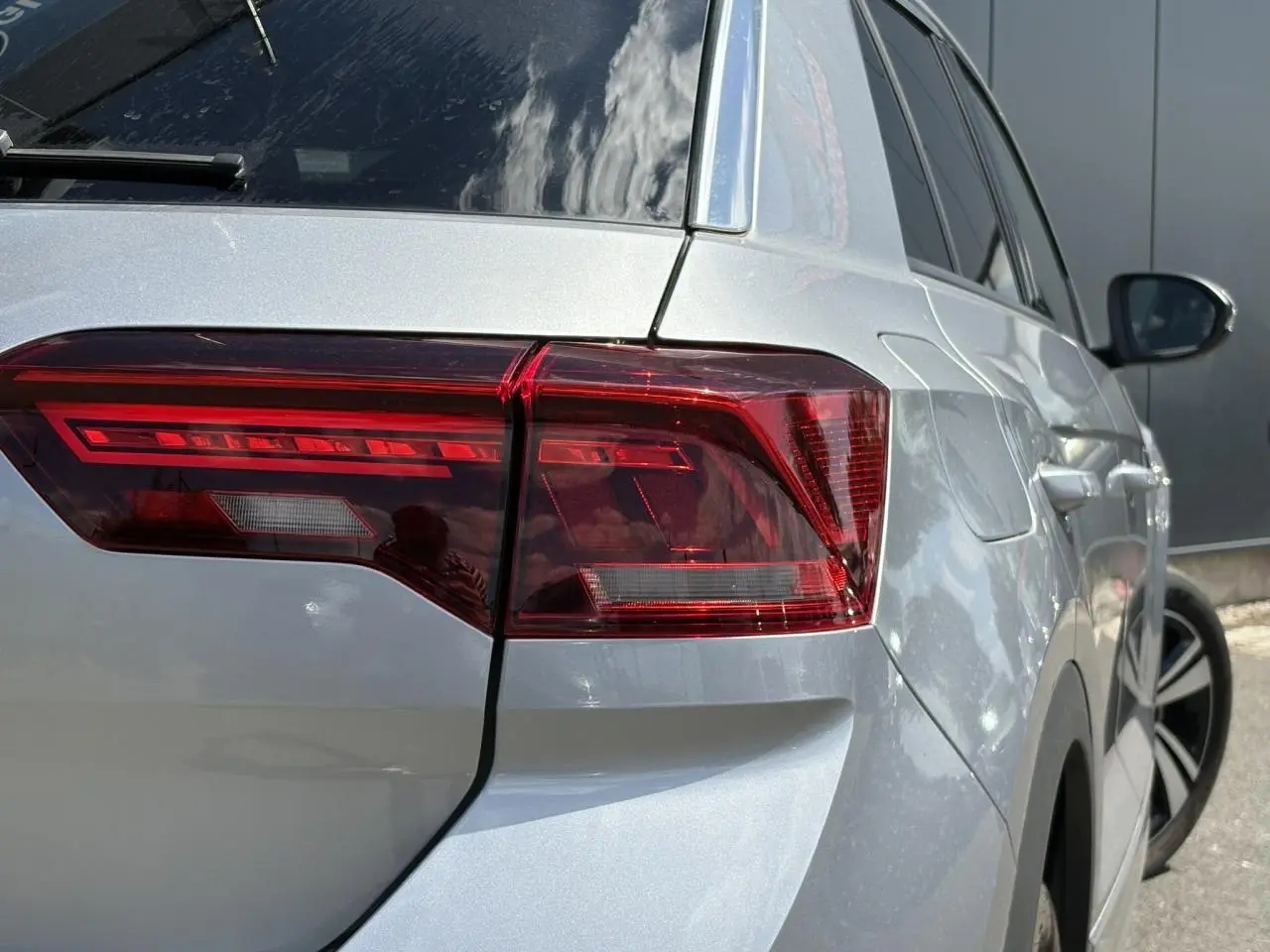 Vue 3/4 arrière droite du Volkswagen T-Roc gris pyrite avec feux arrière LED et jantes alliage visibles.