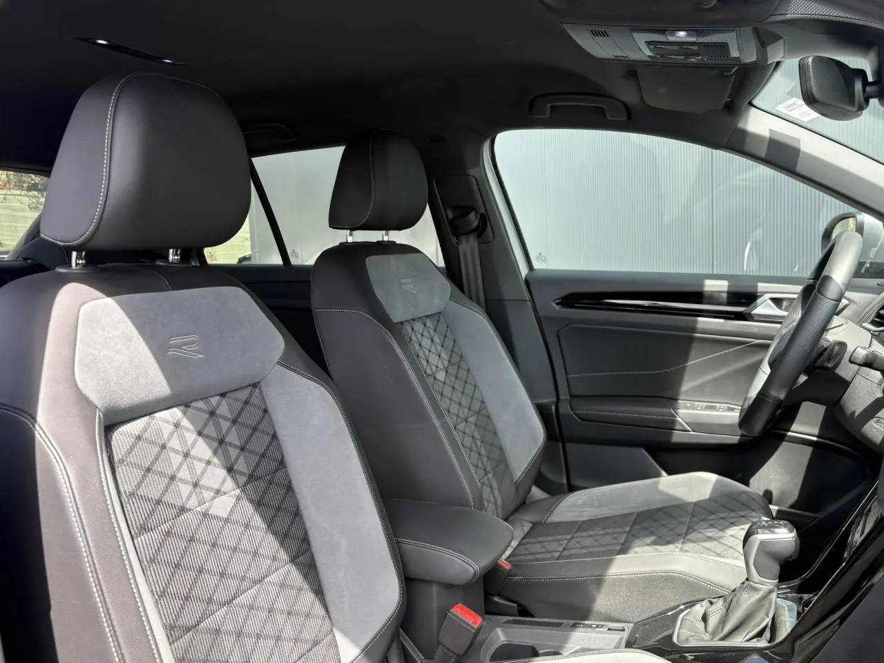 Vue intérieure côté droit du Volkswagen T-Roc 2025, sièges cuir et alcantara gris avec logo R-Line brodé.
