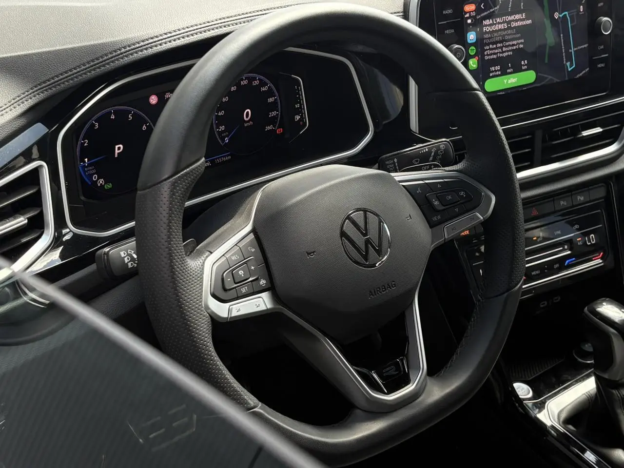 Vue rapprochée du volant cuir noir multifonction Volkswagen T-Roc 2025 avec tableau de bord digital et écran tactile Apple Car Play.