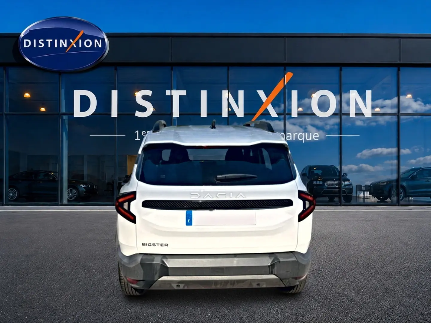 Vue arrière d'un Dacia Bigster blanc garé devant une vitrine avec logo Distinxion, feux arrière LED en forme de C.