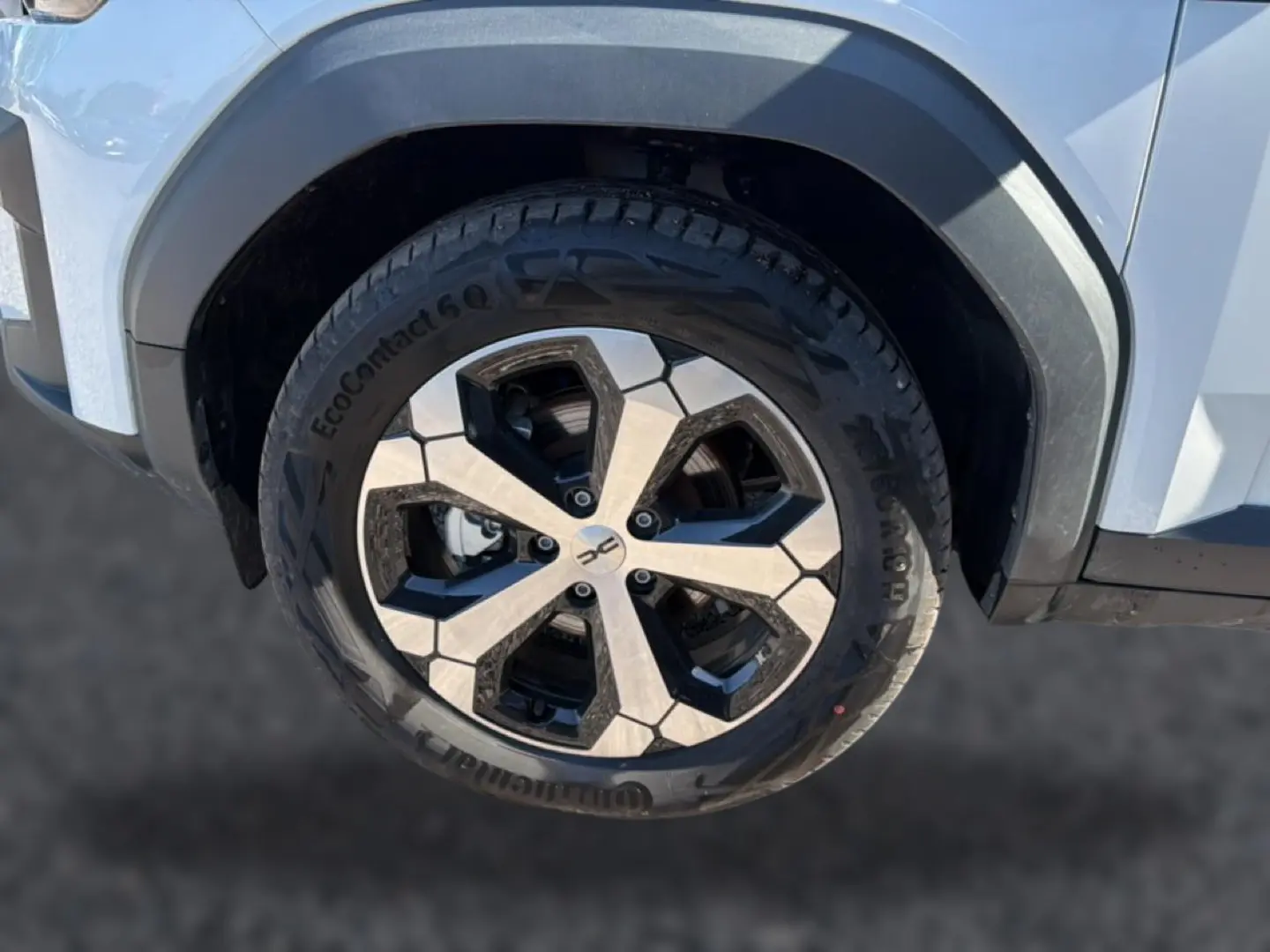 Gros plan sur la roue avant droite du Dacia Bigster blanc, avec jante alu bicolore et pneu Continental.
