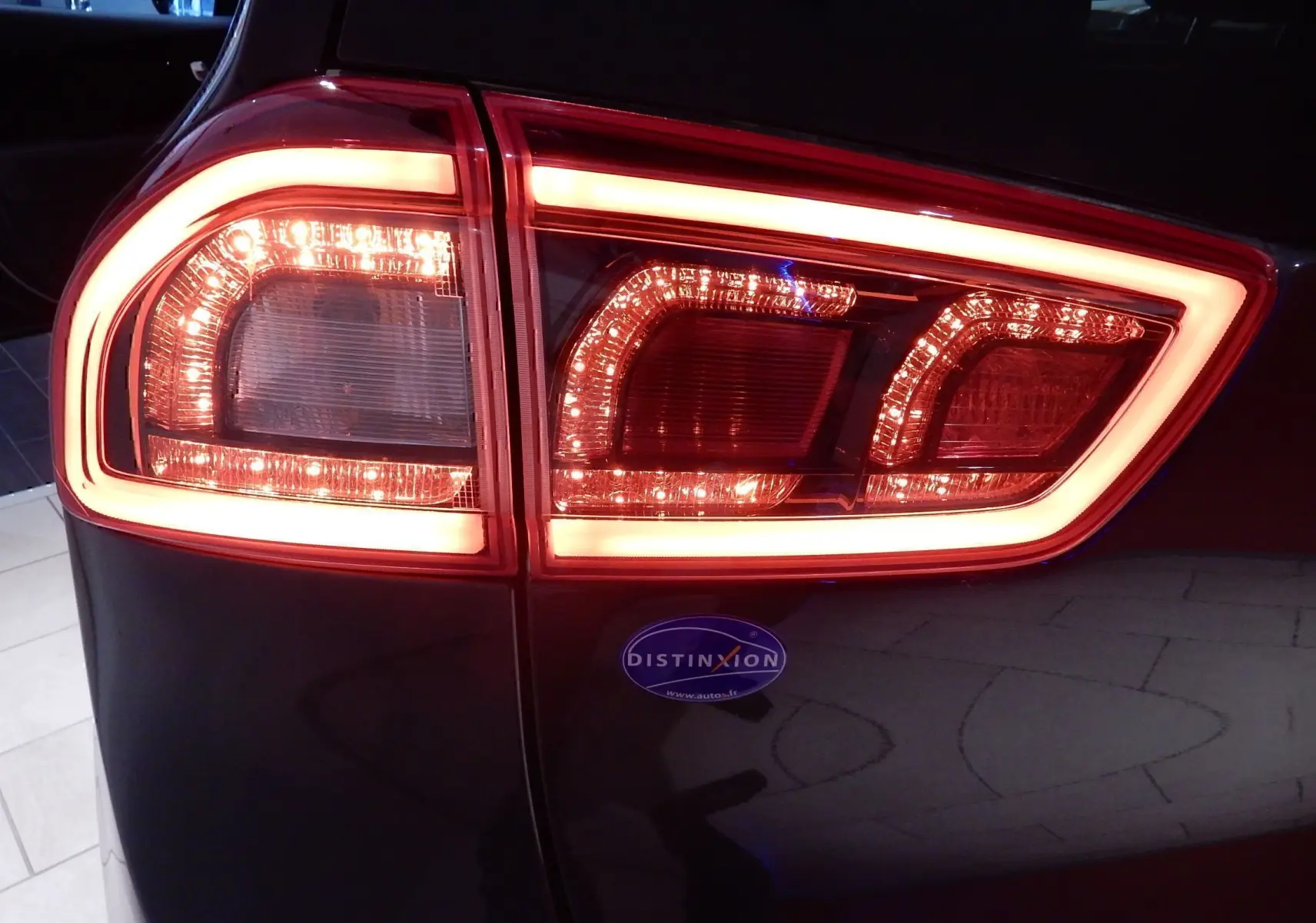 Gros plan sur le feu arrière droit allumé d’un KIA Niro gris galène métal, soulignant son design lumineux distinctif.