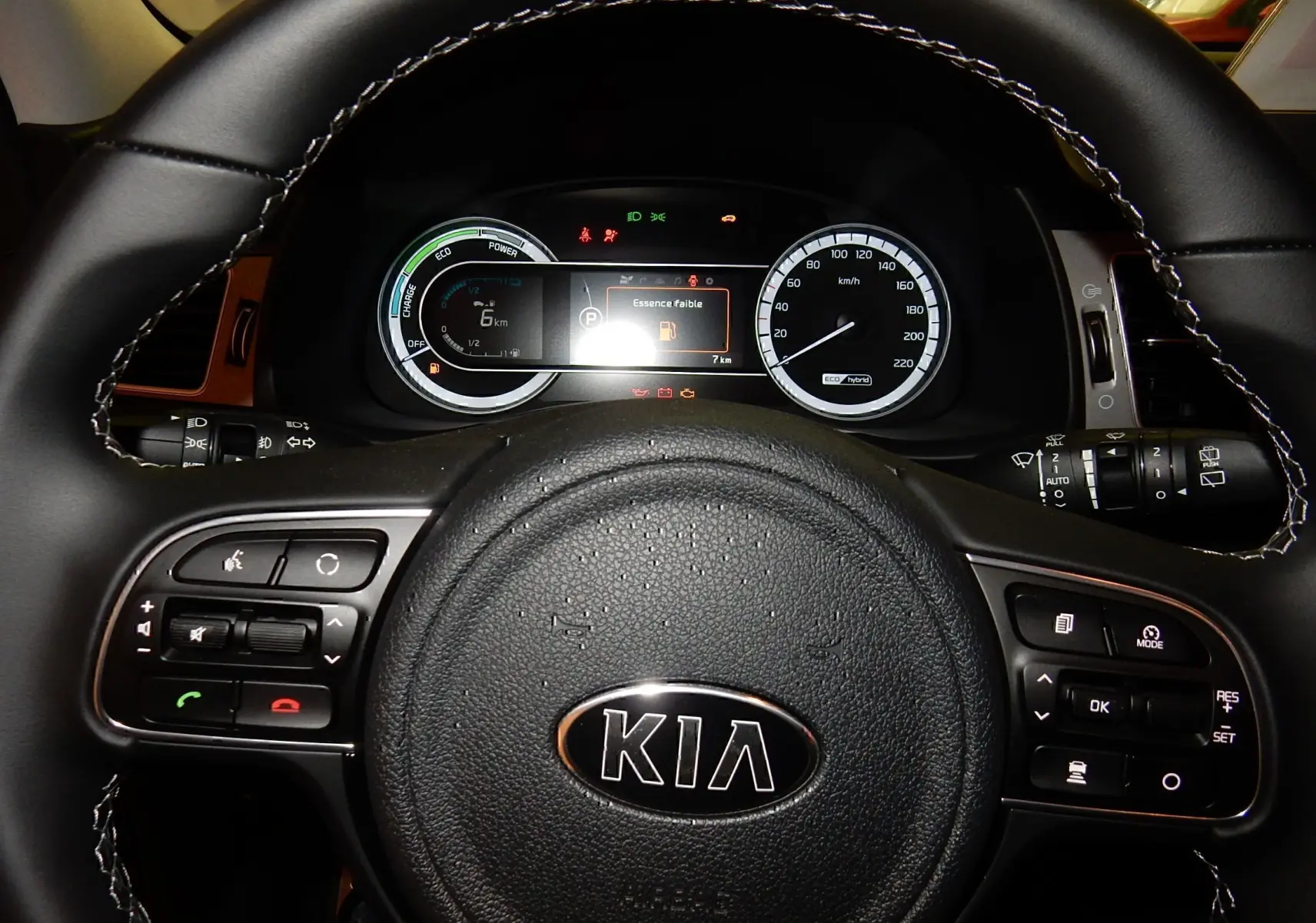 Vue rapprochée du volant noir de la Kia Niro hybride 2019 avec tableau de bord digital et commandes intégrées.