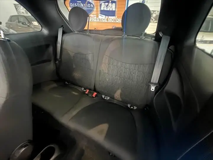 Vue intérieure arrière de la Fiat 500 2023 montrant les sièges noirs avec appuie-têtes et ceintures de sécurité.