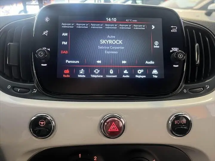 Gros plan sur l'écran multimédia et les commandes du tableau de bord blanc d'une FIAT 500 hybride 2023.