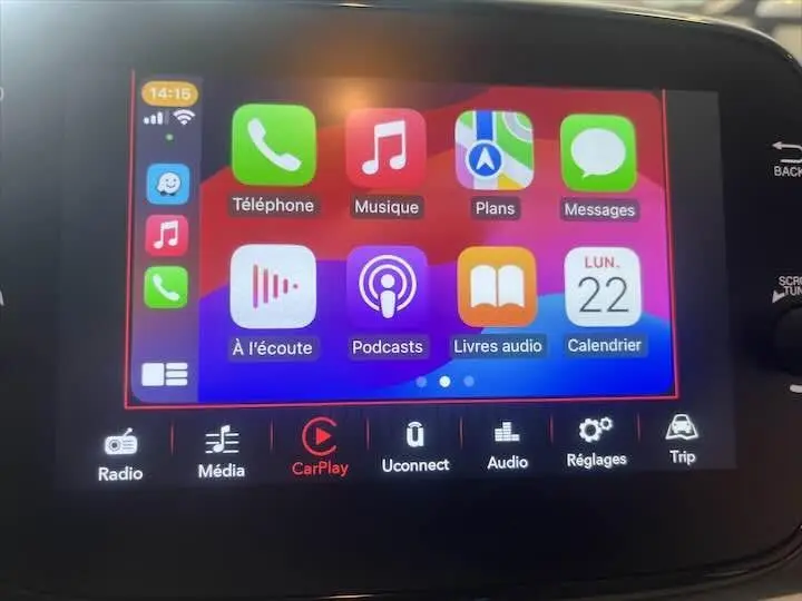 Écran tactile central de la FIAT 500 2023 blanc montrant l'interface Apple CarPlay avec plusieurs applications colorées.