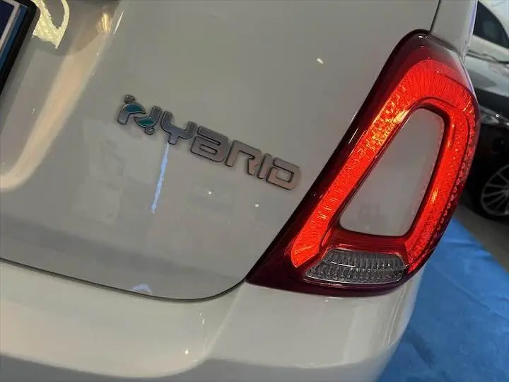 Gros plan sur le feu arrière droit allumé et le badge "Hybrid" sur la partie arrière blanche d'une Fiat 500.
