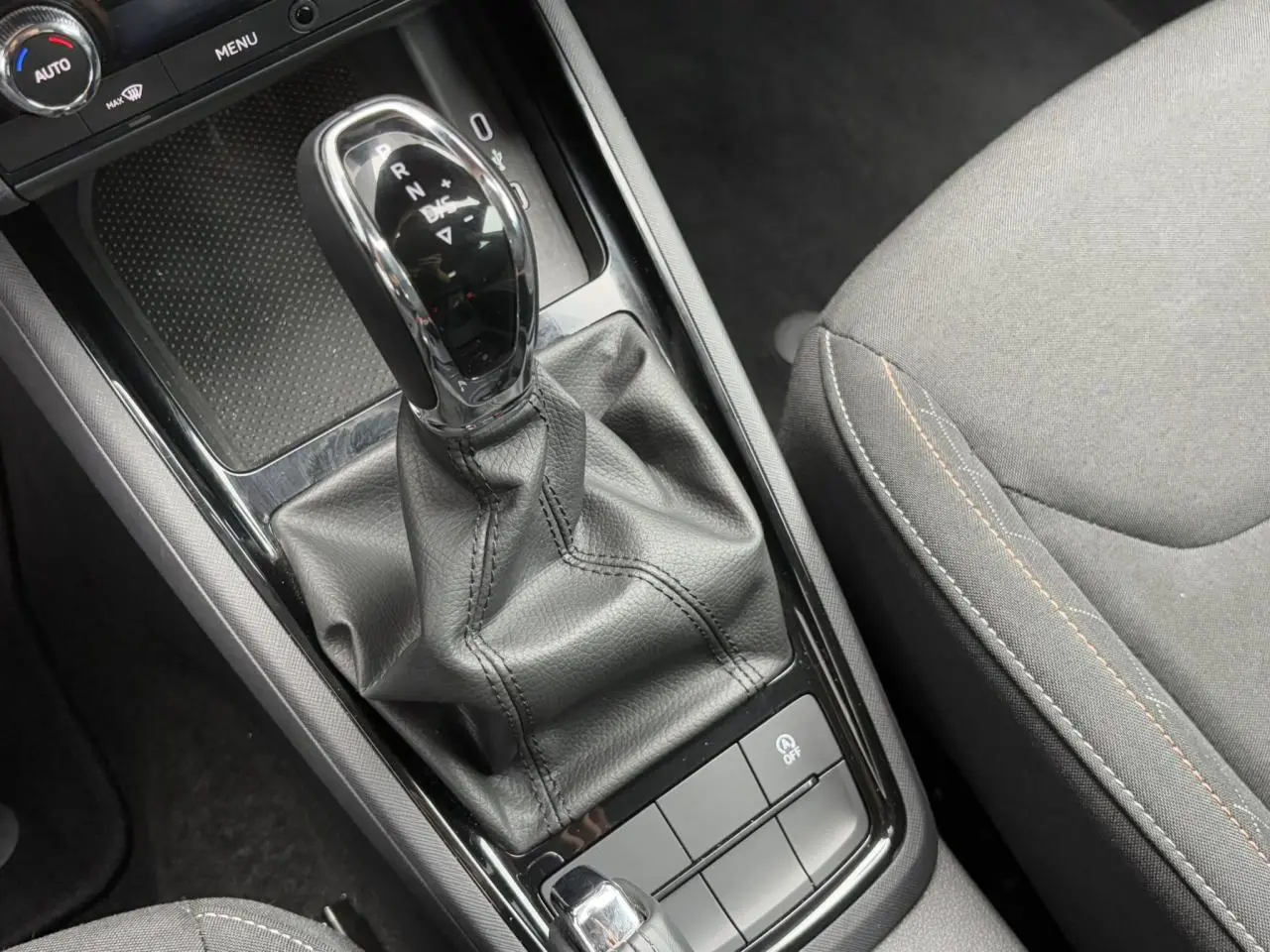 Le levier de vitesse automatique noir et chrome de la Skoda Scala TSI 110 DSG Ambition vu de dessus avec siège gris adjacent.