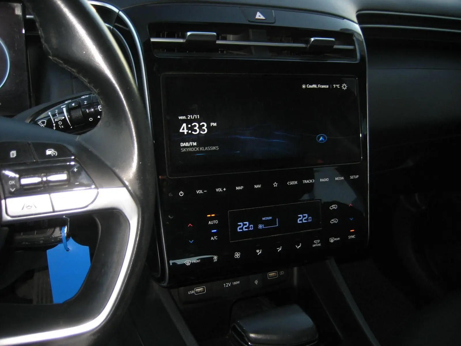 Vue rapprochée de la console centrale et du volant noir du Hyundai Tucson 2022 avec écran tactile et commandes climatisation digitales.