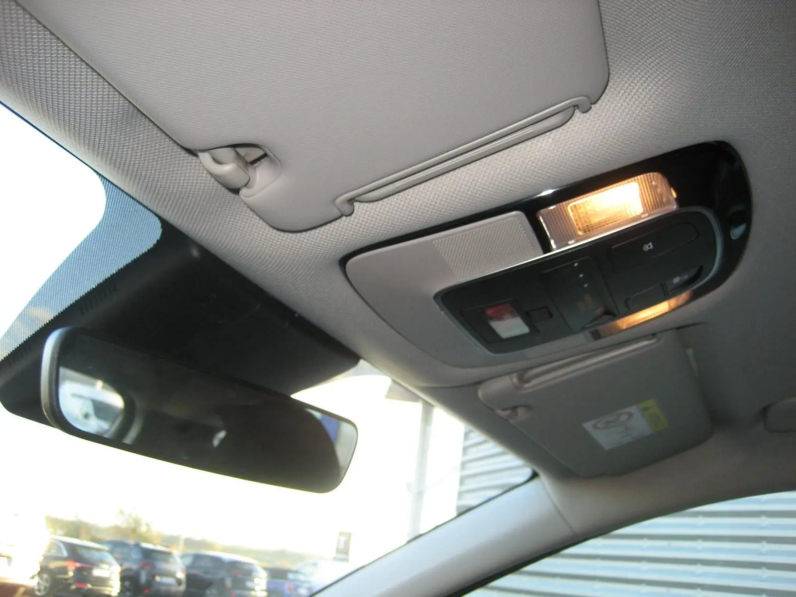 Plafonnier intérieur allumé avec commandes et pare-soleil gris clair dans un Hyundai Tucson noir 2022.