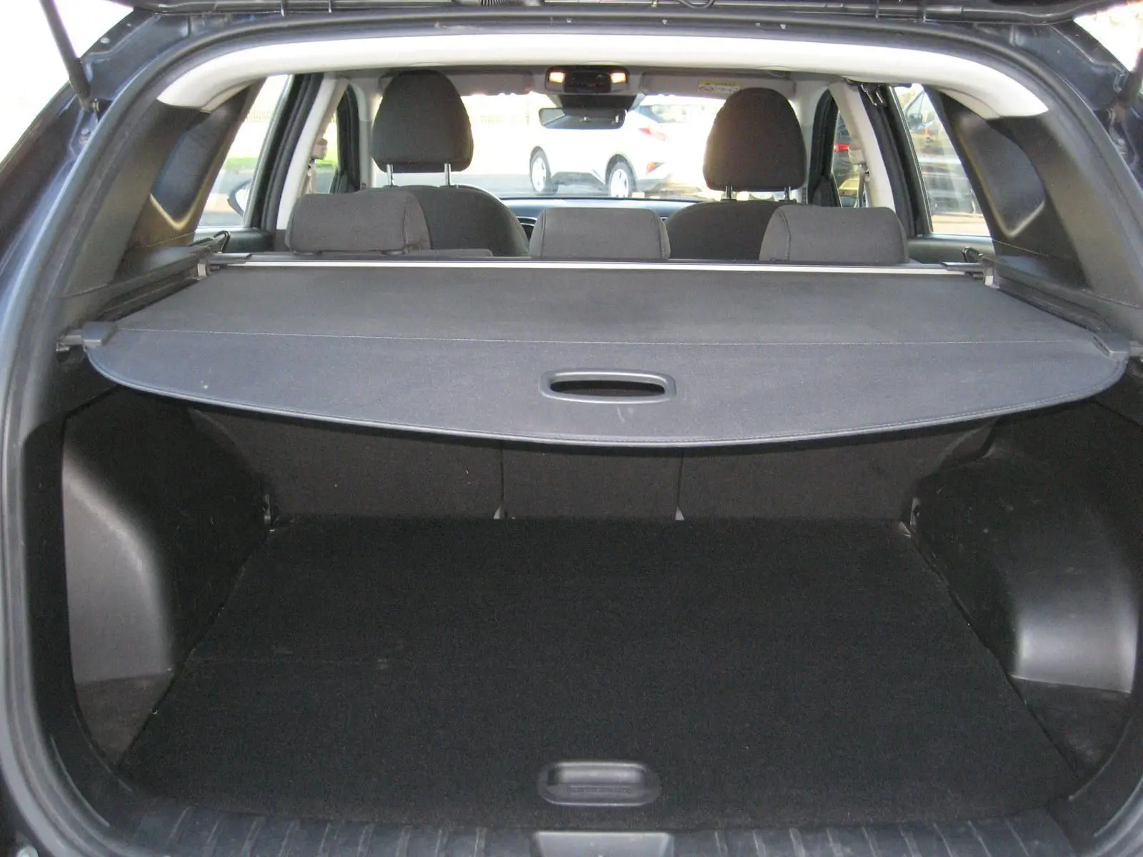 Vue arrière du coffre noir du Hyundai Tucson III 1.6 CRDI hybride 2022 avec cache-bagages déployé.