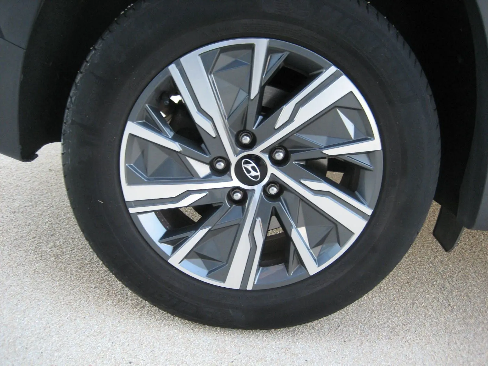 Gros plan sur la jante avant droite du Hyundai Tucson noir 2022, soulignant son design géométrique moderne et le logo Hyundai central.