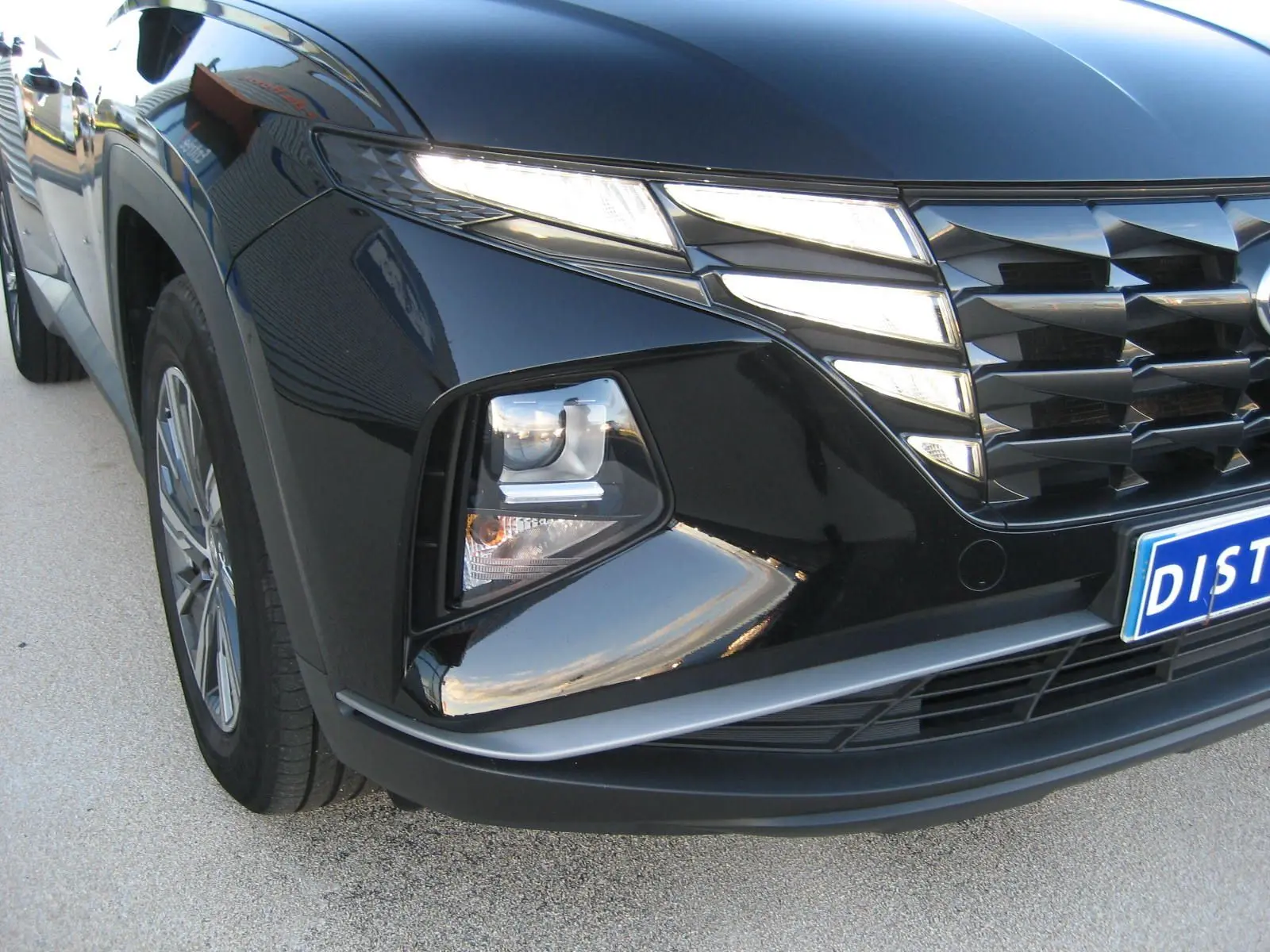 Vue 3/4 avant gauche du Hyundai Tucson noir 2022 mettant en valeur ses phares LED et sa calandre distinctive.