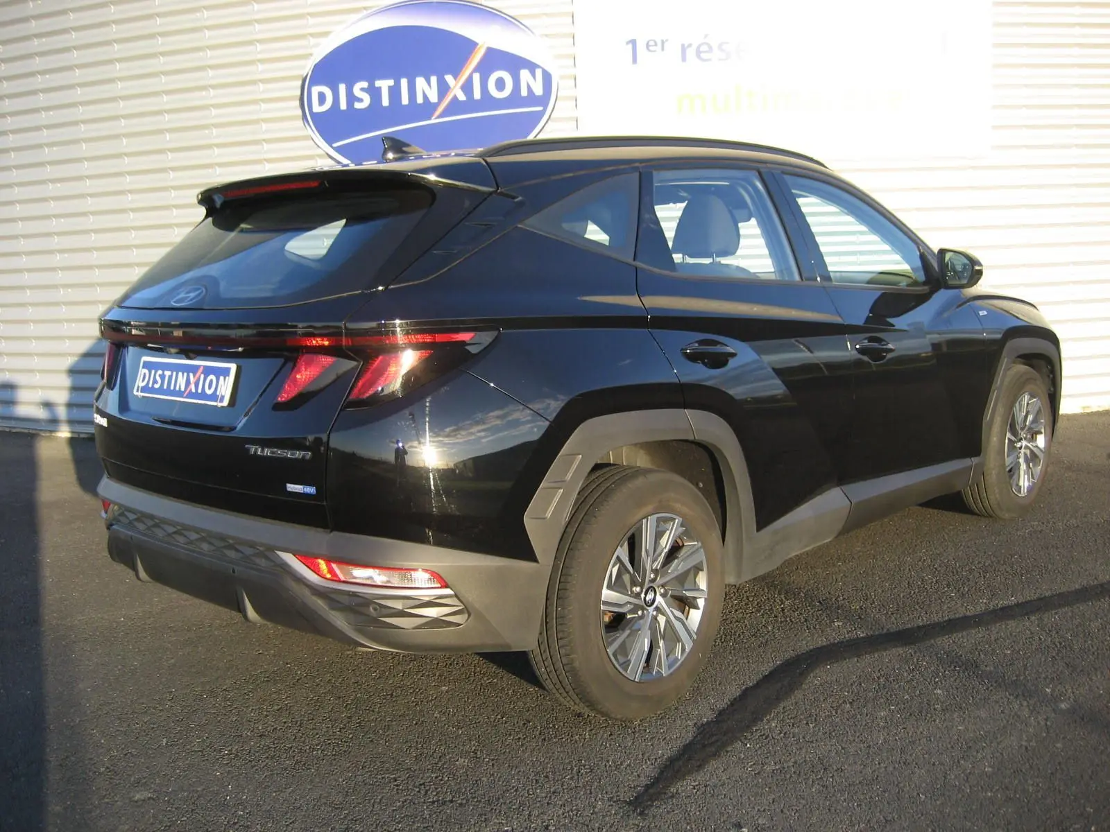 Vue 3/4 arrière droite d'un Hyundai Tucson noir 2022 hybride diesel avec feux arrière LED et jantes alliage.