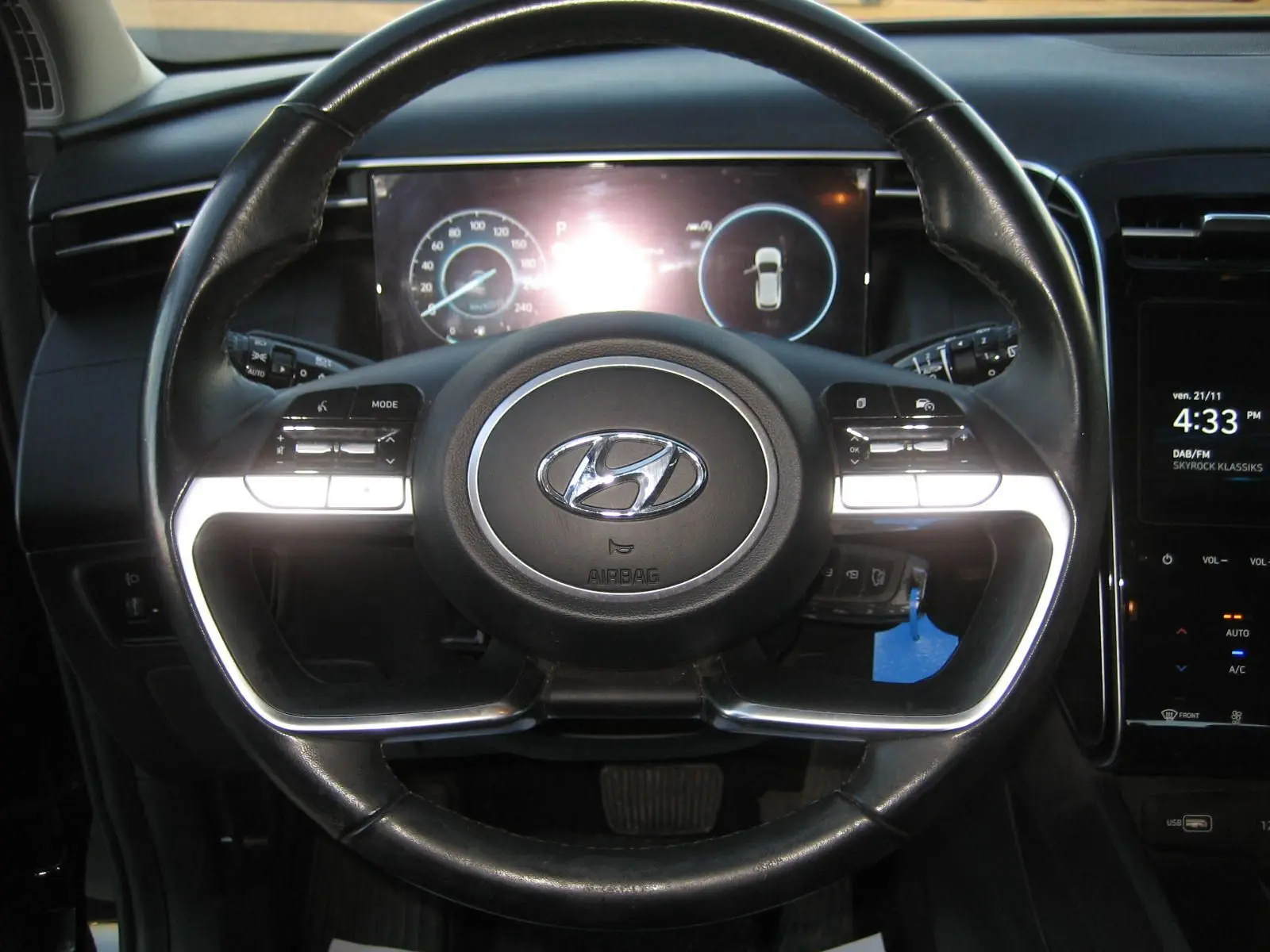 Vue rapprochée du volant noir du Hyundai Tucson III 2022 avec tableau de bord numérique et commandes intégrées.
