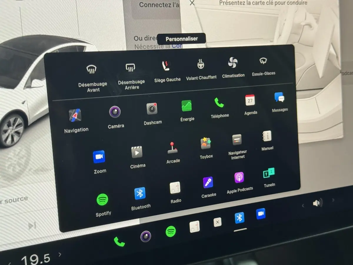 Écran tactile central affichant les options de confort et divertissement du Tesla Model Y blanc en intérieur.