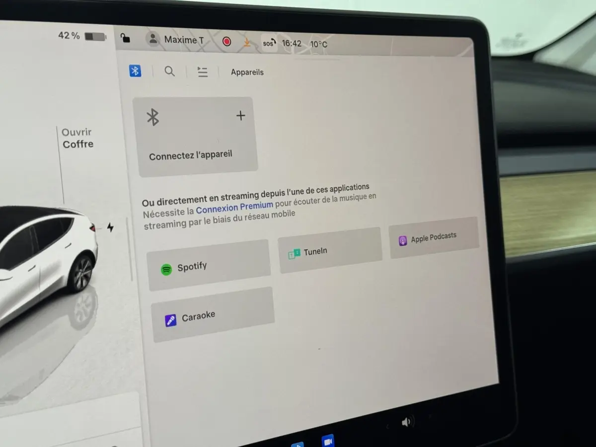 Écran tactile central affichant les options de streaming avec illustration latérale gauche d'une Tesla Model Y blanche.