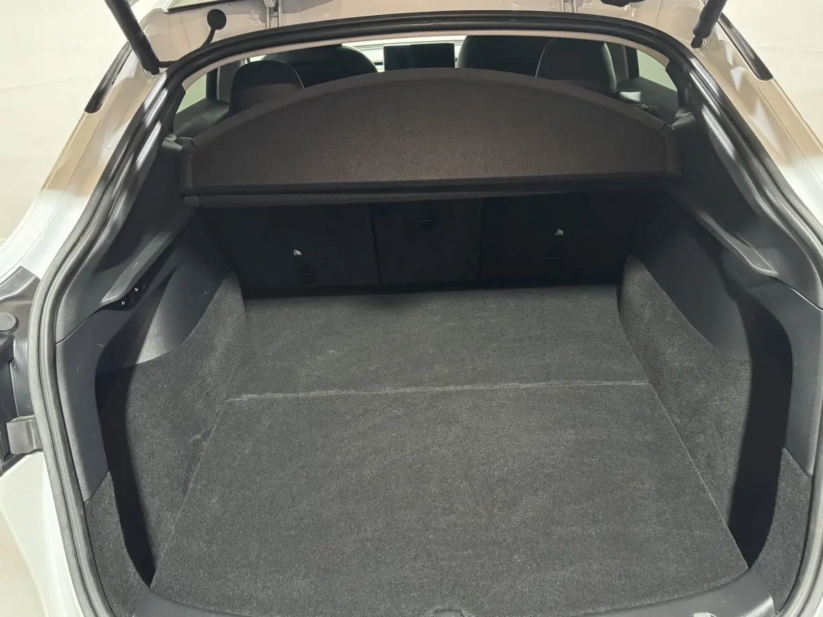 Coffre ouvert d'une Tesla Model Y blanc, vue arrière, montrant un espace de chargement spacieux et propre.