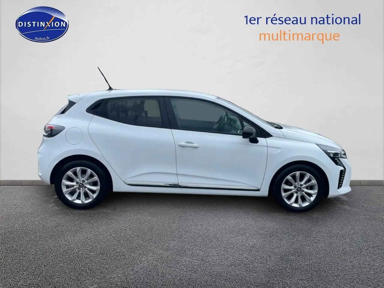 Profil côté droit de la Renault Clio V blanche 2025 avec jantes alliage et vitres teintées sur fond neutre.