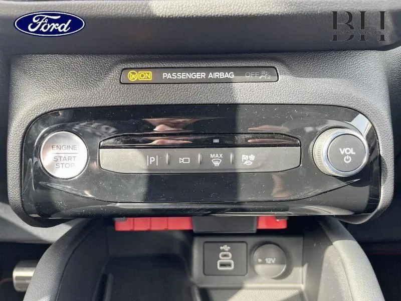 Vue rapprochée du tableau de bord noir brillant du Ford Kuga 2026 avec bouton start/stop et commandes volume.